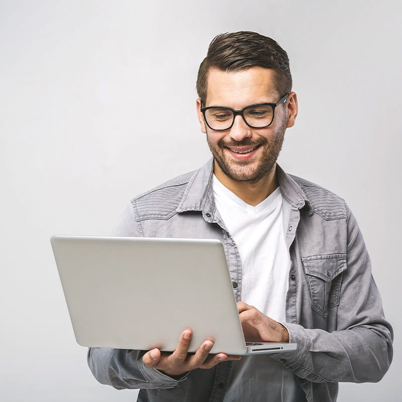 Smiling professional man using a laptop in a bright, modern environment.