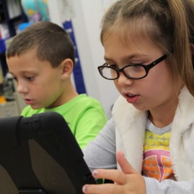 Two students working independently on tablets.
