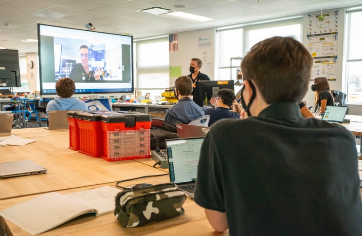 Students watching a virtual lesson on a SMART Board led by a teacher.