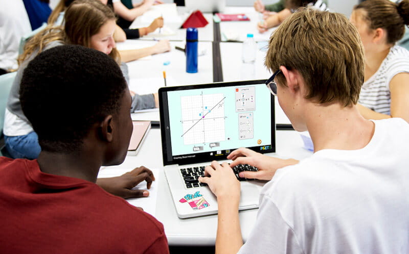 Group of students collaborating on a project with a computer, representing teamwork in education.